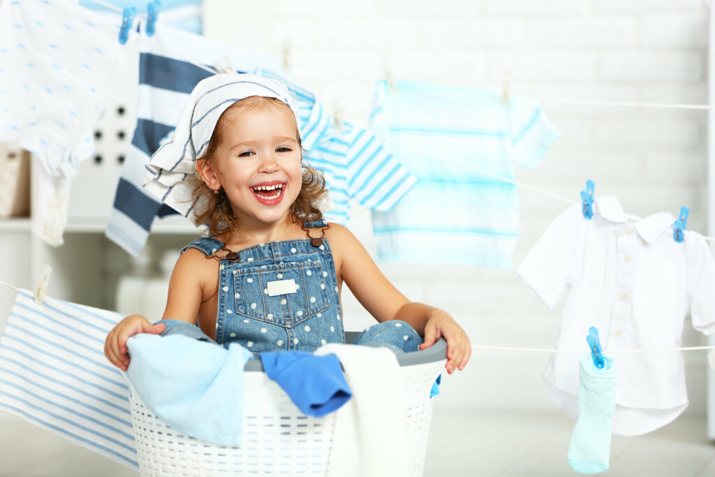 child fun happy little girl to wash clothes and laughs in laundry